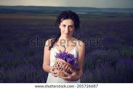 Portrait  of pretty girl with a basket of flowers. Lavender field. Twilight