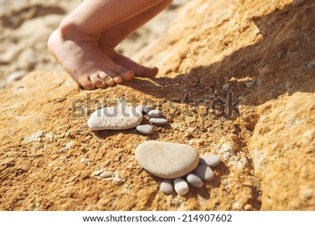 Two pairs of feet: trace feet made of pebble stones and baby feet