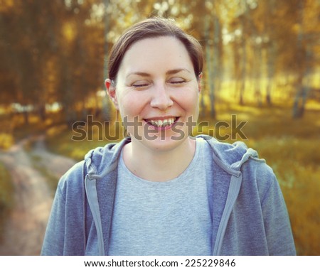 Young attractive woman smiling, eyes closed. Autumn background. Outdoor