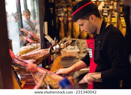 BARCELONA, SPAIN - AUGUST 16, 2013: One of the butcher shops in Barcelona on August 16, 2013. An unidentified seller cutting slices of spanish ham called jamon