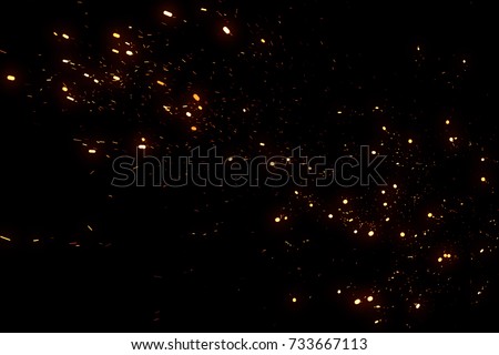 Random flying fire sparks particles isolated on the black background for overlay design.