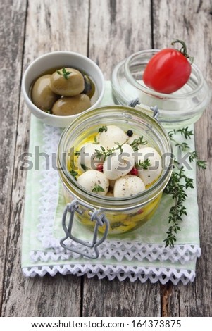 Marinated mozzarella in olive oil, with thyme and pepper, on a wooden background