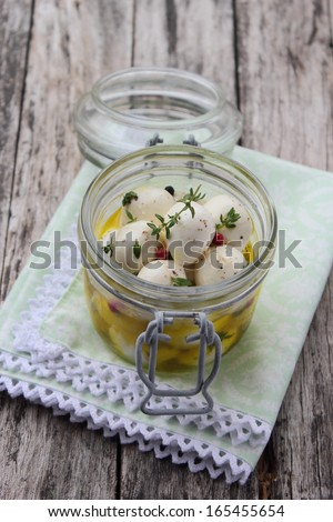 In olive oil marinated mozzarella with thyme and pepper on a wooden background.