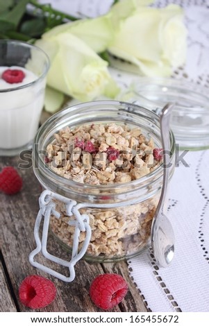 Healthy breakfast with granola, milk and raspberry. Flowers.