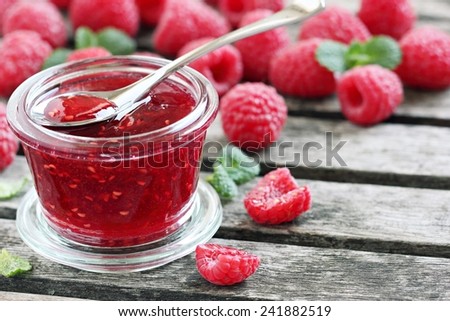 Raspberry jam ( marmalade ) and fresh raspberry on a rustic wooden table.Selective focus.