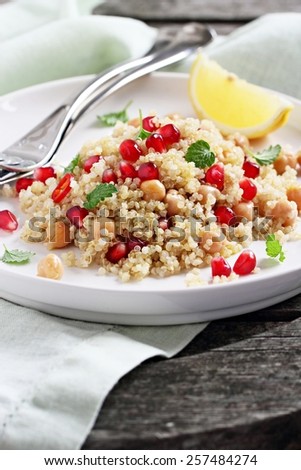 Quinoa salad with chickpeas,pomegranate and mint on a rustic wooden table.Selective focus.