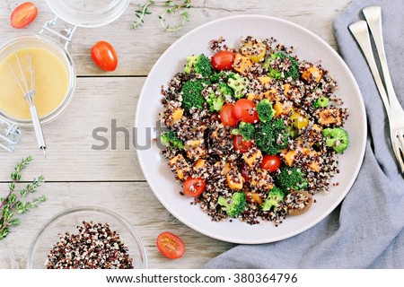 Quinoa salad with broccoli,sweet potatoes and tomatoes on a rustic wooden table.Superfoods concept.Selective focus.
