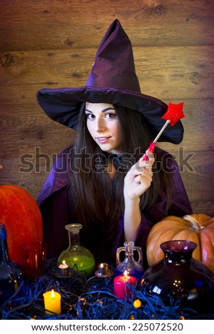 Flirty witch in purple hat with a red magic wand and with a huge pumpkin