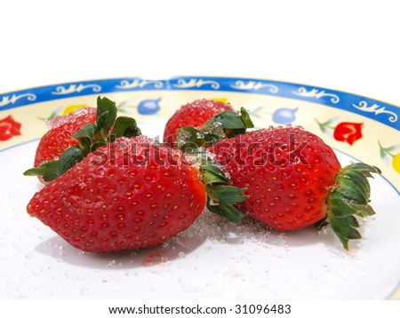 Front view of four fresh ripe strawberries sprinkled with course white sugar on colorful flower pattern decorated dish.