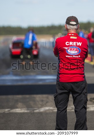 ALASTARO, FINLAND - JULY 7: A crew member is watching preparation for start at the start line of a strip. Image taken in Alastaro, Finland - Nitro Nationals Championships in July 7th 2013.