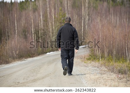 A man walking on the road. Image taken in a spring time.