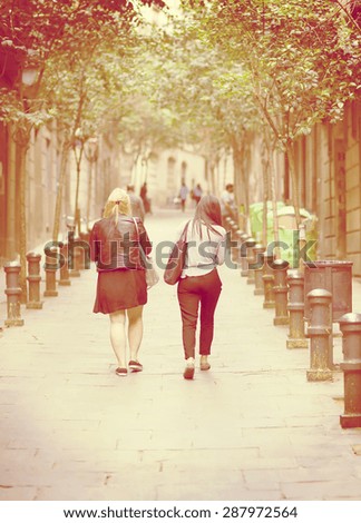 Friends walking in the streets and shopping with bags on their shoulder. Image has a vintage effect.