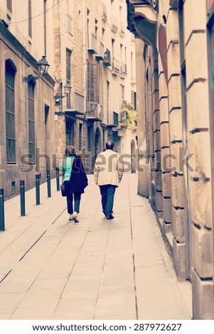 An older couple walking in the narrow streets of Barcelona, Spain. Image has a vintage effect.