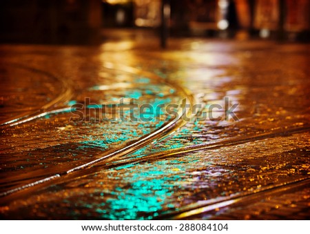 Tram tracks in the night after the rain. Image has a strong instagram and vintage effect.