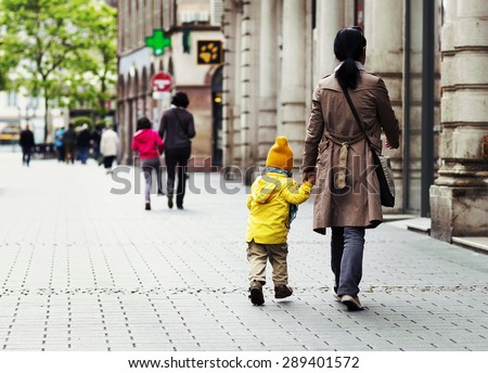 A brown haired is mom taking a child to a kindergarten The boy is jumping happily on the way A brown haired is mom taking a child to a kindergarten The boy is jumping happily on the way