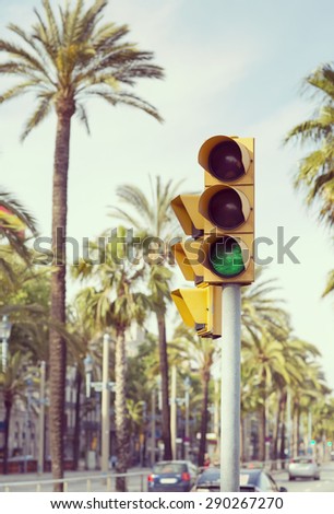 A traffic light showing green next to palm trees in the streets of Barcelona.