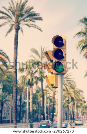 A traffic light showing green next palm trees in the streets of Barcelona.