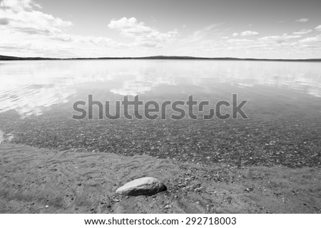 A beautiful scene with crystal clear water in Finland in the summer time. Some clouds in the sky giving a deep contrast to the image. Image has a vintage effect applied.