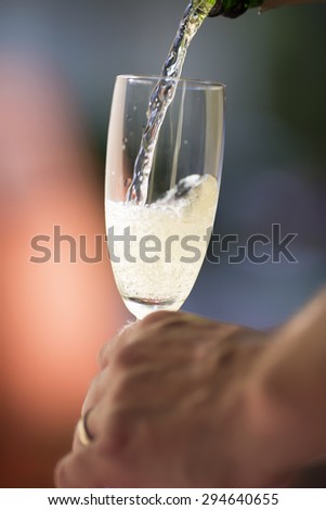 Pouring champagne for a celebration in the summer time outdoor.