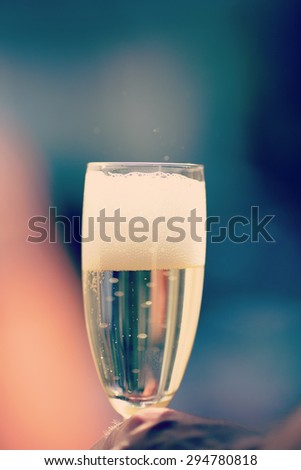 An image of  champagne in a glass in the summer and outdoors. Image has a vintage effect.