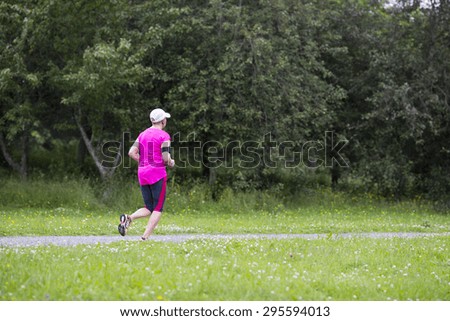 A runner jogging in the summer. Weather is a bit dull and it is raining.