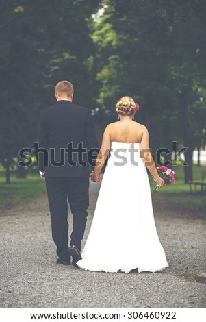 Just married. A lovely shot of just married couple walking towards the future together. Woman has a beautiful wedding dress and man a black suit. Image has a vintage effect applied.