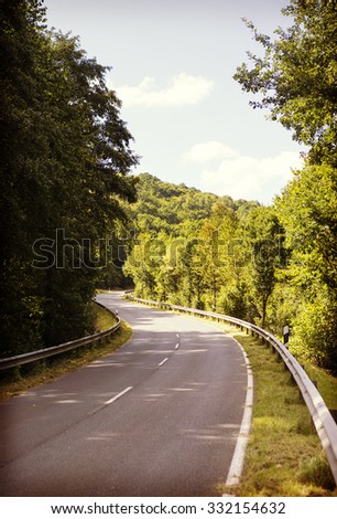 A curvy asphalt road on the mountains. Dangerous road is very narrow and has to be driven slowly. Image has a vintage effect applied.