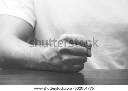 Man is hitting his fist on the table. Image in black and white.