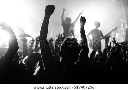 silhouettes of people at a concert in front of the scene in bright light. Black and White
