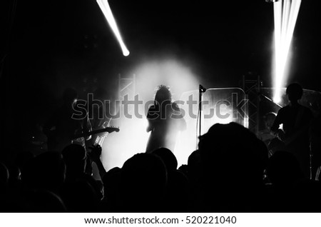 silhouettes of people at a concert in front of the scene in bright light. Christmas party