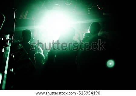 Silhouettes of people in a bright green color in the pop rock concert in front of the stage. That rocks. Party in a club