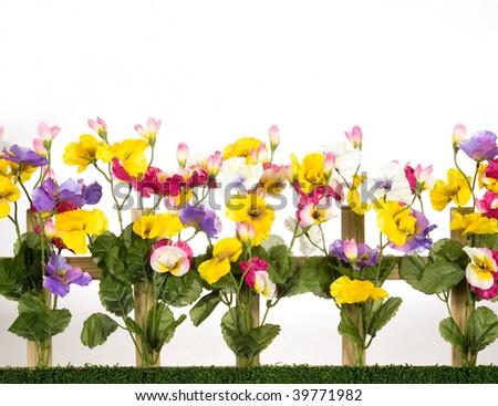 Wooden picket fence with artificial pansies flowers on white background