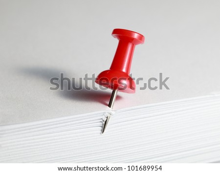 Macro of red drawing pin in paper pile