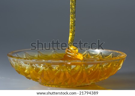 Close-up of honey flow dripping on a glass plate