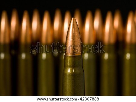 Macro of gun machine bullet over many standing cartridges background