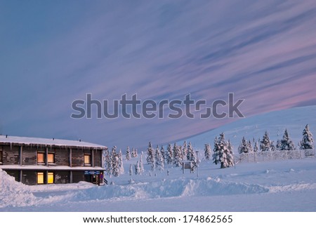 house covered with snow and sunrise. Finland, Lapland