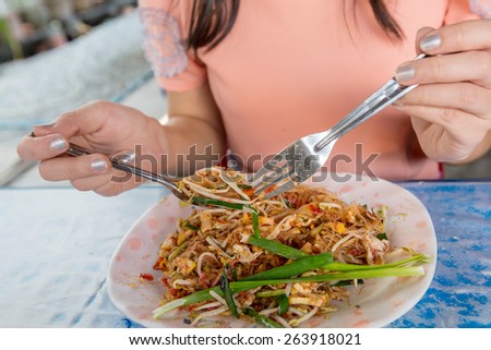 woman eating in a Thai restaurant, close-up on hands and food