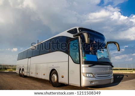 Bus staying in the parking lot under a blue sky with clouds. Lateral view of a bus