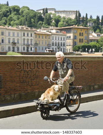 FLORENCE, ITALY - JUNE 6: a man cycles with a dog being carried along with him on June 6, 2013 in Florence, Italy. Florence is a popular tourist destination and the 72nd most visited city in the world