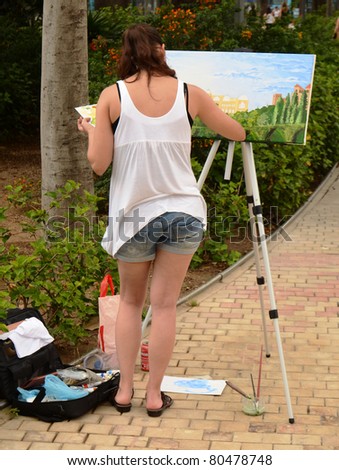 MALAGA, SPAIN - JUNE 25: a woman paints on canvas on June 25, 2011 in Malaga, Spain. Birthplace of Picasso, Malaga is a city in which it is common to find artists painting in the streets and parks.