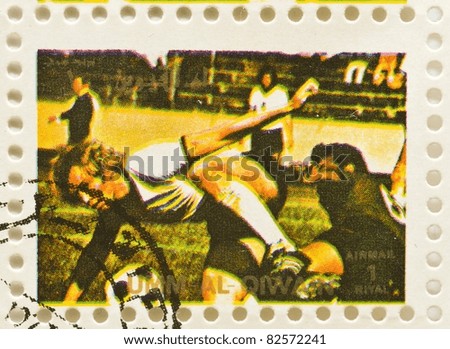 UMM AL-QIWAIN - CIRCA 1973: a stamp from Umm Al-Qiwain shows image of a football player tackling another player, circa 1973
