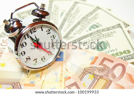 Retro styled alarm clock covered pile of money isolated on white. Time is money concept , dollars, euro