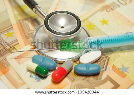 medical concept - health care costs - Stethoscope and syringe on money background and pills