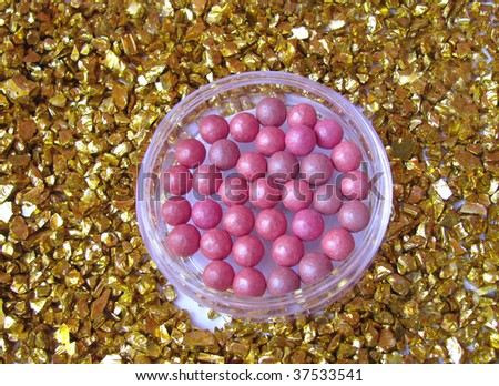 Pink blush on gold background made of little gold rocks