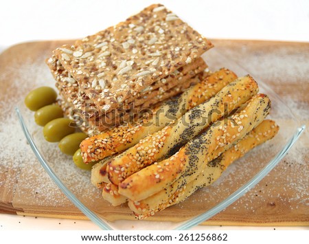 salty sticks with sesame and poppy seeds, Bread sticks or Pretzel sticks,linen tiles and olives