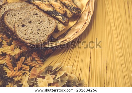Variety of types and shapes of Italian pasta. Dry pasta background with slice of bread and salty sticks