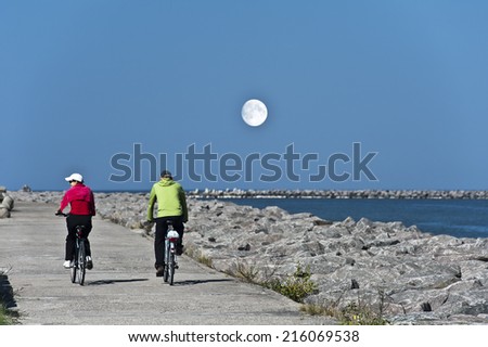 couple cycling on the pier with moon