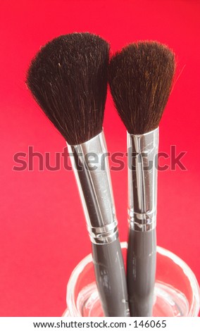 Makeup brushes against a red background