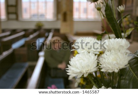 person in silent prayer with flowers in the foreground