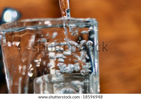 glass being filled with water and overflowing with bubbles